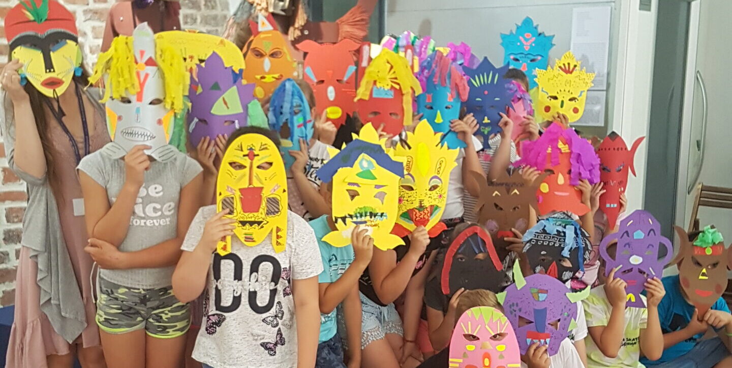 Zdjęcie przedstawia grupę dzieci w kolorowych maskach.