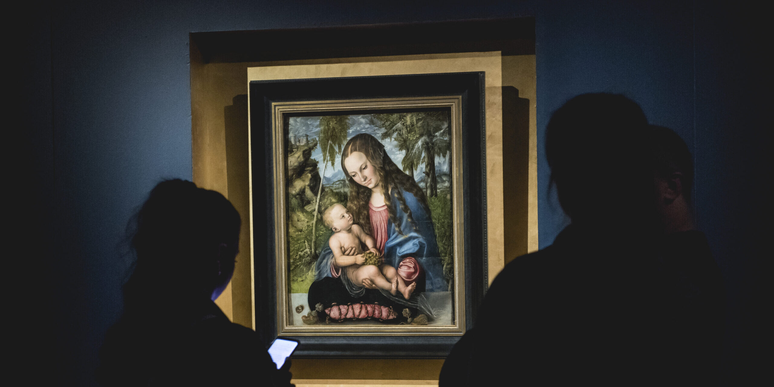 W centralnej części zdjęcia znajduje się obraz Madonny z dzieciątkiem, po bokach cienie dwóch osób