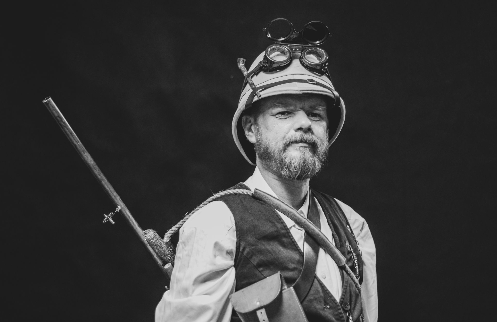 Fotografia przedstawia Przemysława Krupskiego w półpostaci z hełmem i okularami na głowie i karabinem na plecach.