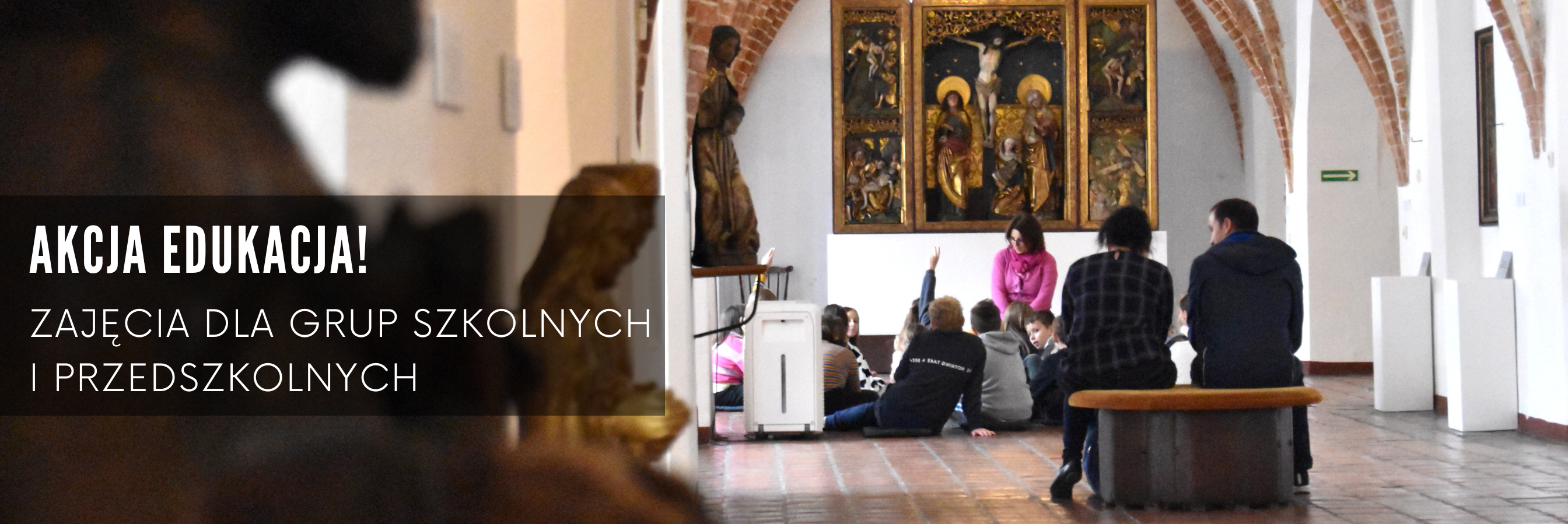 Baner ze zdjęciem przedstawiającym dzieci siedzące na poduszkach w muzeum i słuchające muzealniczki, napis Akcja Edukacja, zajęcia dla grup szkolnych i przedszkolnych
