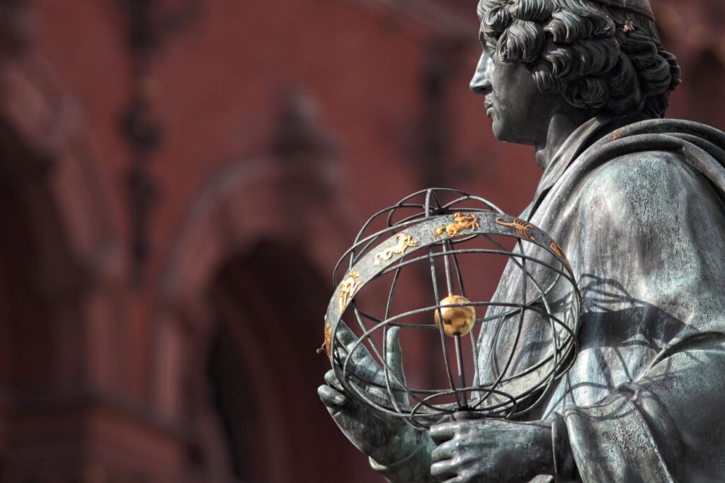 Mikołaj Kopernik posąg na tle budynku z czerwonej cegły