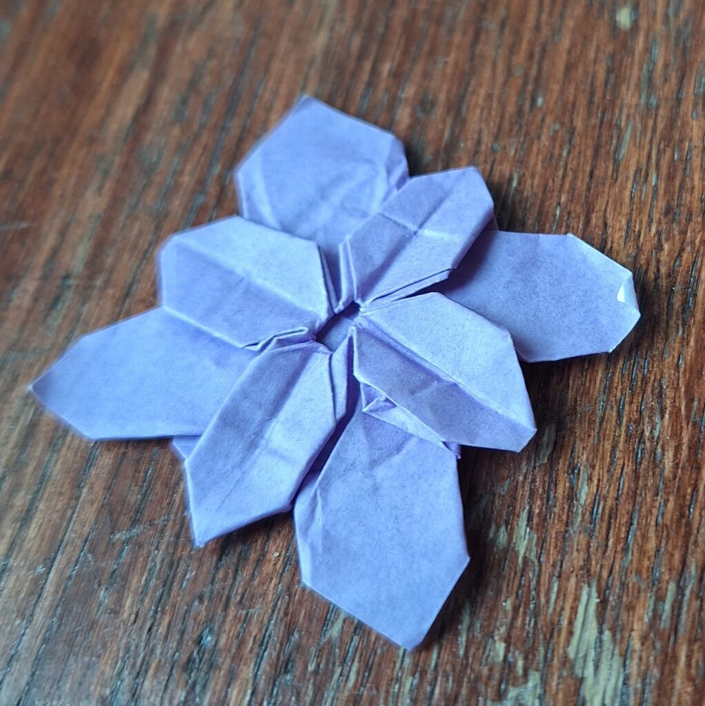 Granatowy papier w kształcie kwiatu na drewnianym tle.