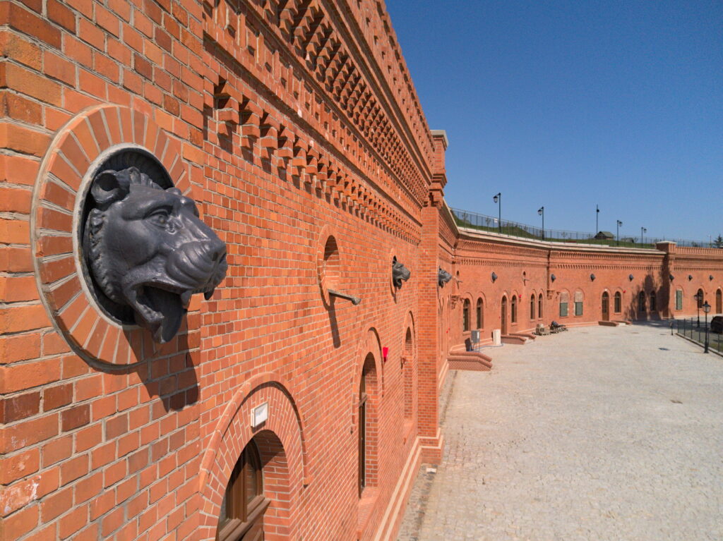 Pomarańczowe forteczne mury z żygaczem w kształcie lwa na pierwszym planie