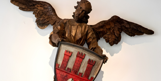 Drewniany anioł trzymający tarcze z herbem miasta Torunia.
